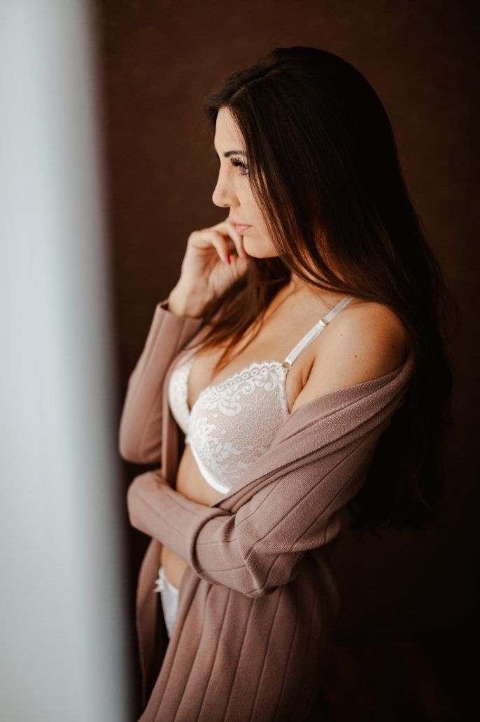 sensual Portrait einer Frau in Dessous steht im Schlafzimmer und schaut aus den Fenster