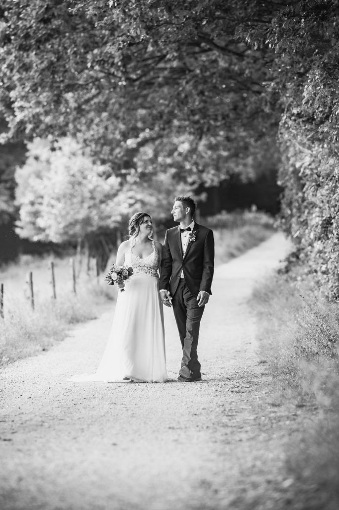 Brautpaar läuft einen Feldweg entlang in schwarzweiß
