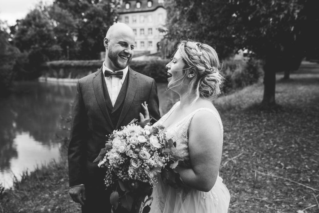 Braut und Bräutigam scherzen beim Shooting für die Hochzeitsfotos im Schlosspark