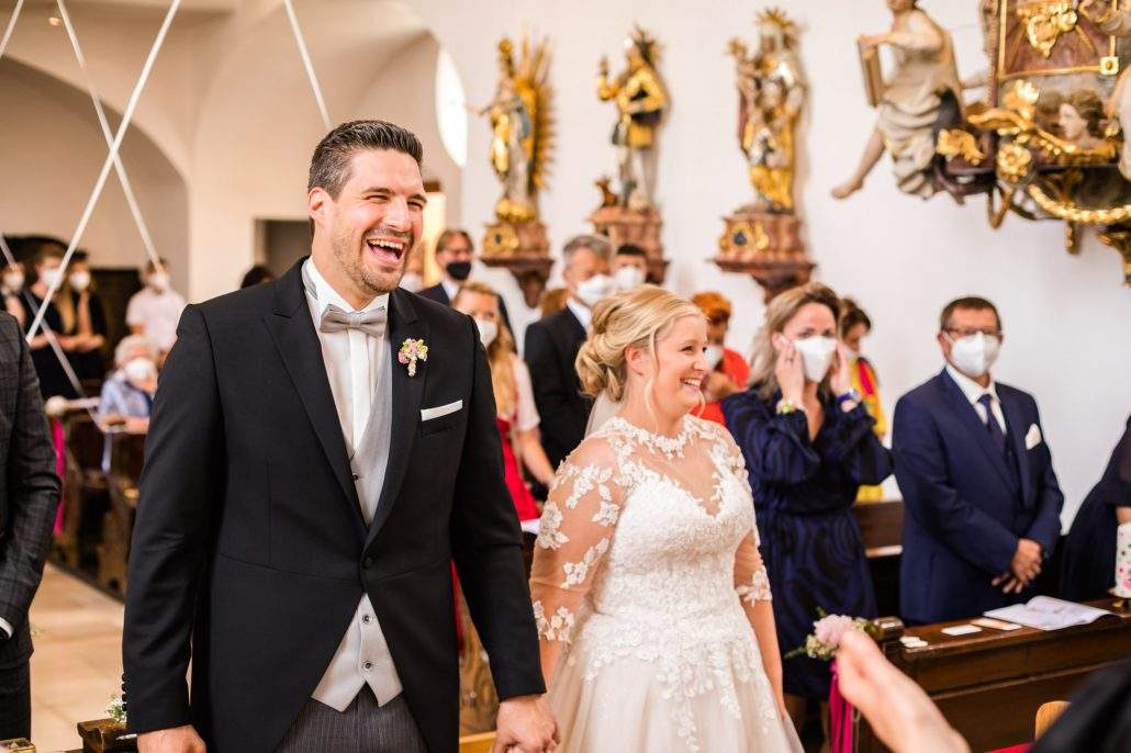 Brautpaar lacht während der Predigt des Pfarrers in der Kirche im Kreis Bamberg