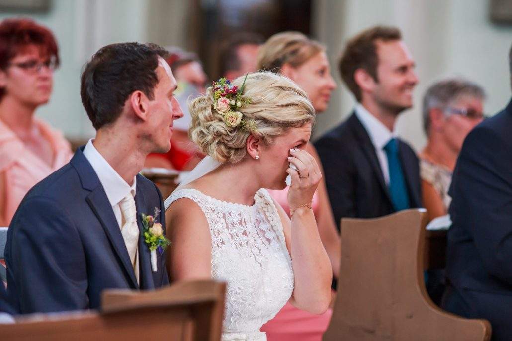 Braut wischt sich in der Kirche die Freudentränen aus dem Gesicht.