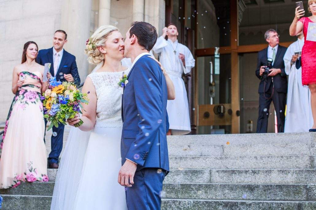 frisch getrautes Paar küsst sich auf der Kirchentreppe in Eltmann