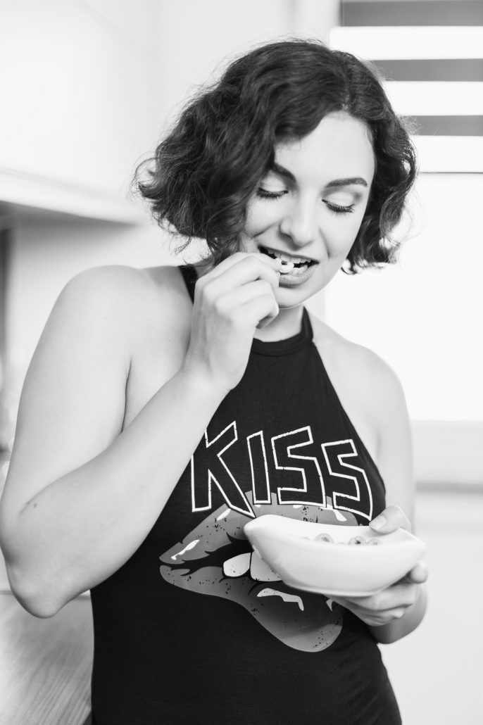 sensual Portrait einer Frau mit Kiss T-Shirt steht in der Küche und isst