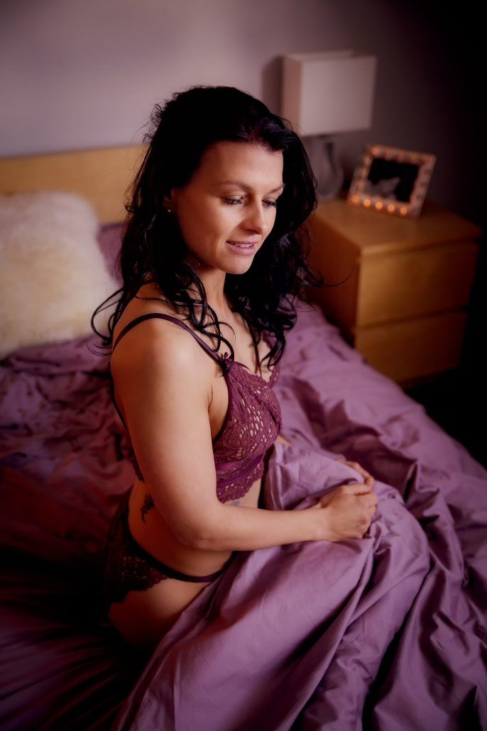sensual Portrait einer Frau in sexy Dessous kniet im Bett