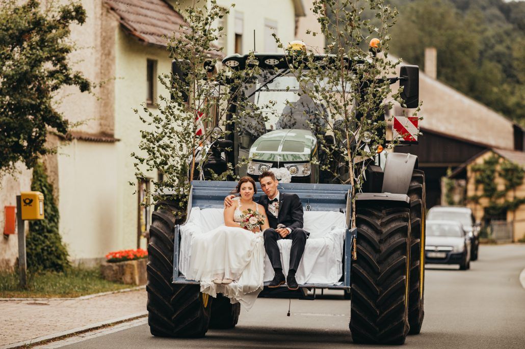 Brautpaar nutzt einen Traktor als Brautauto am Tag der Hochzeit