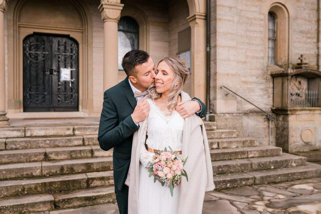 Brautpaar nach der Hochzeit vor der Kirche im Winter beim Brautpaarshooting