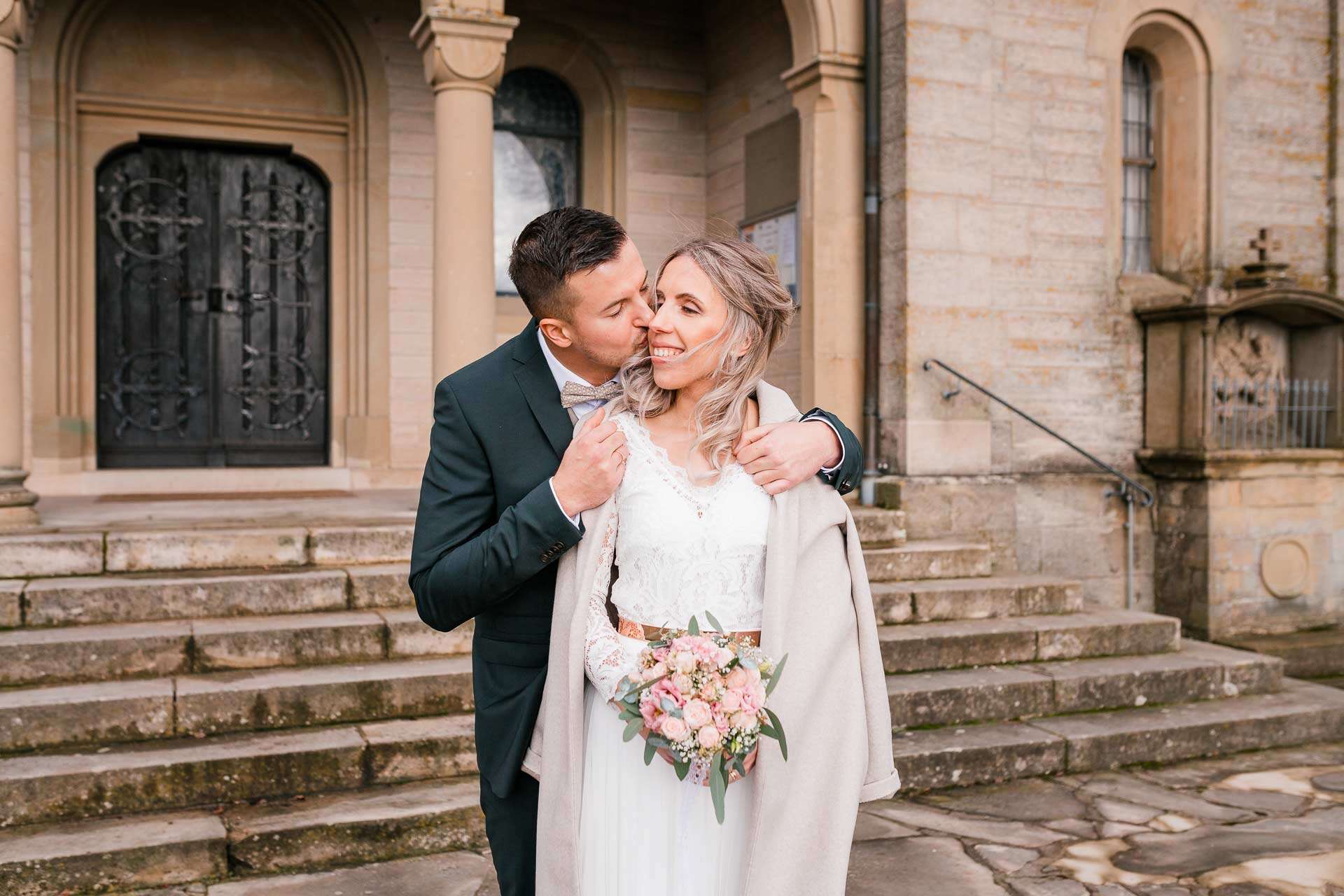 Brautpaar nach der Hochzeit vor der Kirche im Winter beim Brautpaarshooting